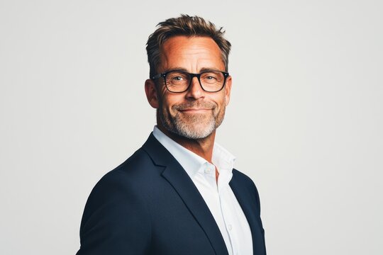 Professional man smiling in smart attire with glasses against a plain background