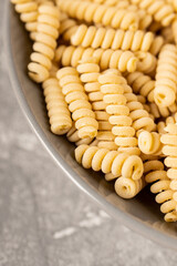 Raw dry fusilli bucati pasta in the plate. Selective focus. Shallow depth of field.
