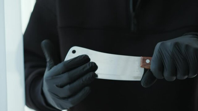 A man holds a sharp ax in his hands.
A man with a bladed weapon.
A killer with a knife and black rubber gloves.
A man is about to commit murder.
Sharp ax
