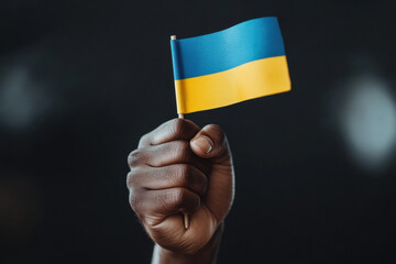 Hand holding ukrainian flag on dark background showing support