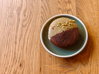 Delicious chocolate cookies with hazelnuts, half glazed, on a light wooden table, top view. Space for text.