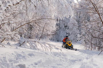 Athlete on a snowmobile moving in the winter forest in the mountains of the Southern Urals