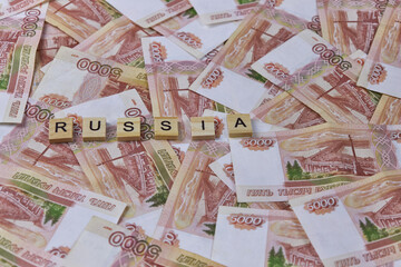 Background of five thousand Russian ruble banknotes with inscription RUSSIA on wooden blocks, currency exchange, accumulation of cash, banking system
