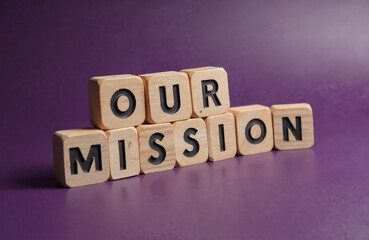 Obraz premium Our Mission message written on wooden blocks with purple background. Business concept of company statement, corporate aim, core value, guiding principle, long-term strategy.