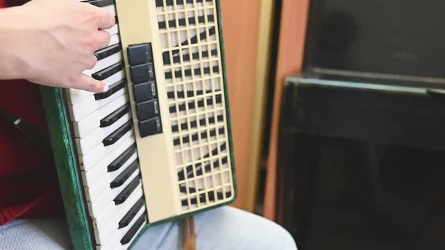 Close-up of accordion keys as a woman in a red sweater plays with focus. The black and white keys contrast beautifully, showcasing the intricate details and rhythmic precision of the performance