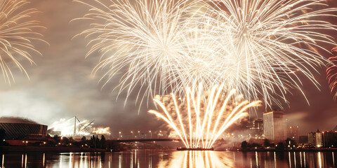 Naklejka premium Spectacular fireworks festival celebration over river cityscape night view vibrant atmosphere stunning visuals