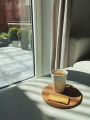 A cup of coffee and biscuit on a table a sunny day