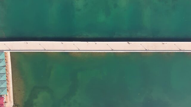 Aerial top down pan of De Bosset Bridge in Kefalonia, Greece, stretching over calm turquoise waters