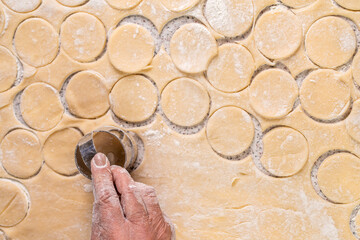 Cutting circles of dough a metal round shaped knife. Preparation of the dough for baking, large piece of the dough is on the table and the chef cuts out small circles on it with an iron shape