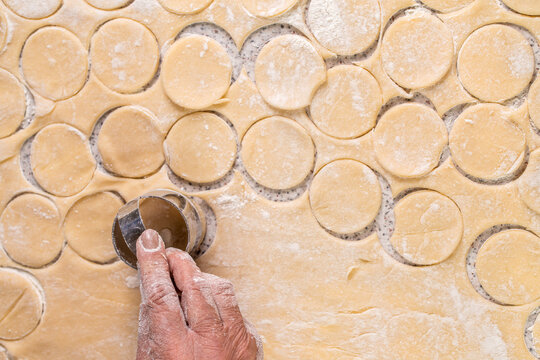 Cutting circles of dough a metal round shaped knife. Preparation of the dough for baking, large piece of the dough is on the table and the chef cuts out small circles on it with an iron shape