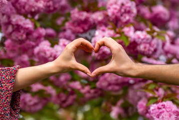 Closeup of couple making heart shape with hands. Hands women and men are heart the hands. Beautiful...