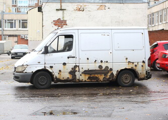 An old white rusty minibus stands near the walls of the household block, Podvoysky Street, St. Petersburg, Russia, October 23, 2024