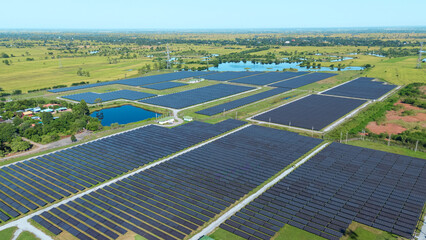 Drone shot aerial view solar energy array provides renewable power in large scale facility surrounded by greenery and water in rural place. Solar farm at the countryside