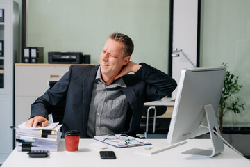 Overworked young businessman office worker suffering from neck pain after had a long day at her office desk.