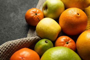 A basket of fruit including apples, oranges, and tangerines. The basket is on a counter or table