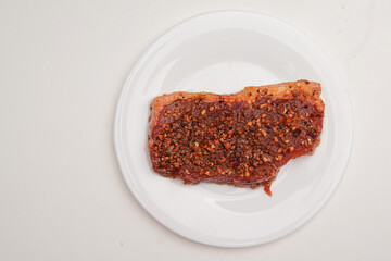 Marinated meat covered in spices and sauce. prepared inside a box, ready to be cooked.