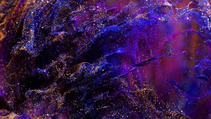 Golden and blue particles are mixing in a purple liquid, creating beautiful swirling patterns and textures, perfect for visual effects or motion graphics projects