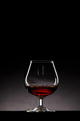 Elegantly Captured Glass of Amber Liquid Set Against a Dark Background, Highlighting the Curvaceous...