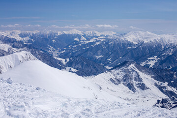 Breathtaking Winter Landscape: Snow-Capped Mountains Stretching into the Distance with Bright Blue Skies and Puffy Clouds Above, Inviting Adventure and Exploration