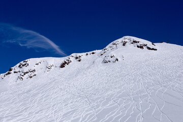 A Vast Winter Wonderland: Snow-Covered Mountain Peaks Under Clear Blue Sky with Skiing Trails