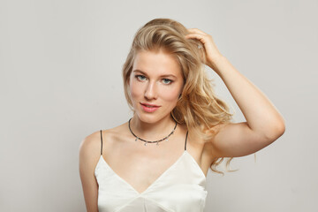 Fototapeta premium Fashionable young blond female model with clear skin, soft make-up and healthy hair and natural emotional expression portrait shot. Blonde woman on white background