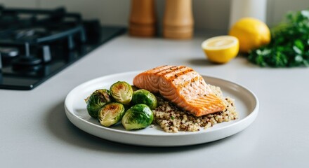 Grilled salmon with quinoa and Brussels sprouts on white plate, half lemon parsley in background Modern kitchen setting
