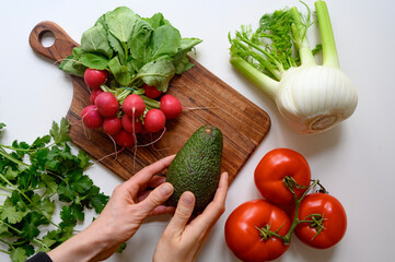 Hands preparing healthy food or salad. Fresh vegetables and herbs on the table. 