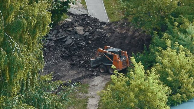 Skid steer loader removing asphalt from road construction site