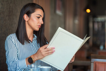 Obraz premium Businesswoman reading menu in restaurant deciding what to order