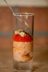 A deliciously layered dessert artfully served in a beautiful glass, topped with a variety of fresh ingredients