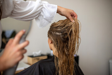 Fototapeta premium women hairdresser makes the models blonde wet hair by spraying hairspray