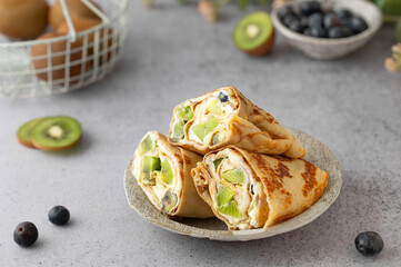 Crepe roll cake with cream cheese and Kiwifruit kiwi and blueberries. Crêpes or thin pancakes with...