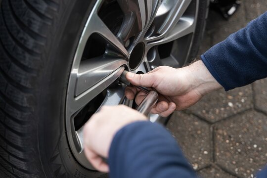A man performs seasonal tire changes and prepares a car for winter or summer, demonstrating care in maintenance. Preparing for the season and changing tires