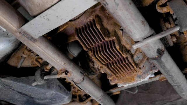 Close up of the underside of a used rusty car. The rear end differential and other suspension parts need maintenence. Rotating movement shot in 4k.