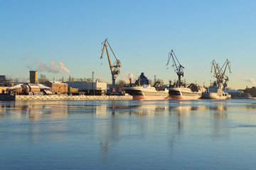 Moored ship and harbour cranes in port on Neva river