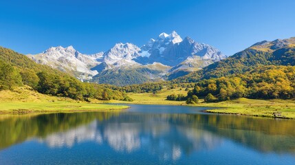 Fototapeta premium Scenic alpine lake mirroring snow-capped mountain peaks under a clear blue sky during a bright sunny day.