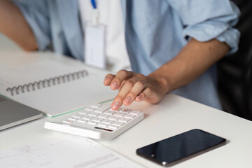 Close-up of a financial professional using a calculator for data analysis in an office.