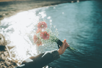 キラキラした水面とピンクの花束　手元　シネマティック　フィルム風