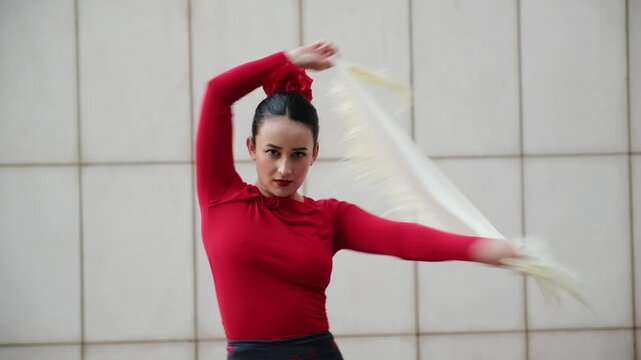 Young woman flamenco dancer is dancing with manila shawl in front of white tiled wall