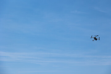 Flying drone in action against the blue sky. Aerial video filming concept.