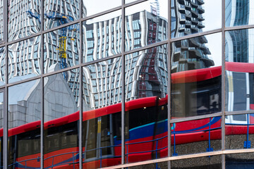 Reflection of a London double-decker bus on a glass facade with urban architecture in the background.
