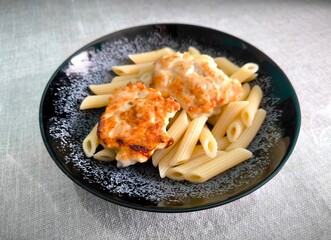 a black and white plate with pasta and meat on the table