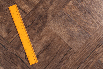 One orange ruler on wooden table, top view. Space for text