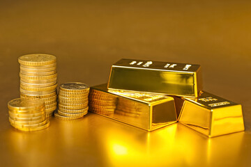Gold bars and coins on shiny background, closeup