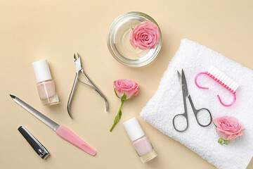 Set of pedicure tools and flowers on beige background, flat lay