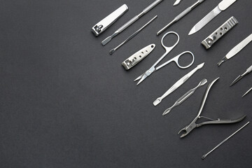 Set of pedicure tools on black background, flat lay. Space for text