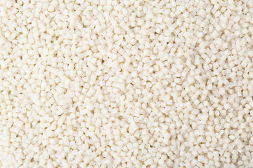 Pile of plastic granules as background, top view
