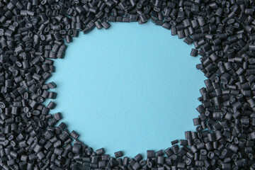 Frame of black plastic granules on light blue background, top view. Space for text