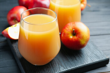 Refreshing apple juice in glass and fruits on black wooden table, closeup