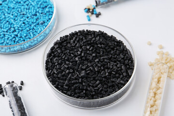 Colorful plastic granules in petri dishes and test tubes on white background, closeup